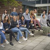 Previous summer school students sitting on a bench outside the building