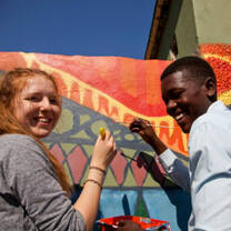 Volunteers on a project paint a mural