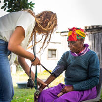 A health intern gives an elderly woman a check-up