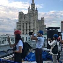 Student posing on the rooftop of the building in Moscow city center next to one of the "Seven Sisters" building
