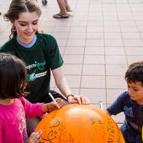 A Projects Abroad Human Rights intern helps local children sign a balloon during a community outreach day in Córdoba, Argentina