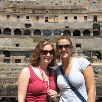 Two young women wearing sunglasses stand in front of the Colosseum