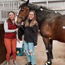 Participant brushing and grooming a horse under the guidance of an instructor in Scotland’s summer equine program.