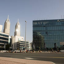 A large glass building with the name Hult stands to the right of a white building with two towers