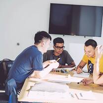 A group of young students sits around a table working on a project