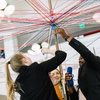 Students add stickers to a pole supported by multicoloured strings