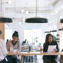 One male and two female students sit at a long table in a cafe