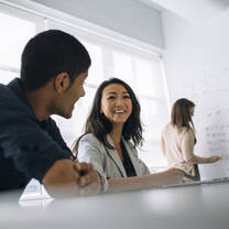 One male and two female postgraduate students work on a business analytics project in a meeting room