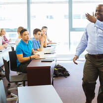 A professor stands in front of a class of young students