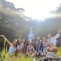 A group of happy people in front of a waterfall