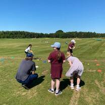 Students in a golf program teaching local children basic golf skills on a practice course.