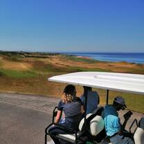 Students exploring the coastal fairways of Kingsbarns Golf Links by golf cart in Scotland.