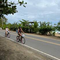 Two girls ride bikes together. 
