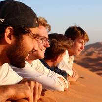 Students laying stomach down on a dune