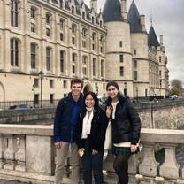 Students posing on bridge by castle in Paris