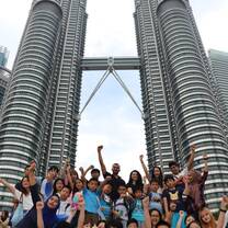 students smiling in front of two skyscrapers