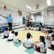 kids sitting in a circle with a teacher speaking