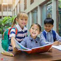 three children reading a book together 