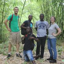 two volunteers standing with three men in forest