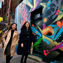 2 students walk next to a mural wall