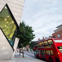 Red London bus driving past London Met grad center