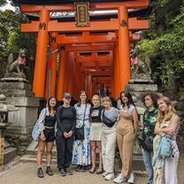 group smiling in front or red gate