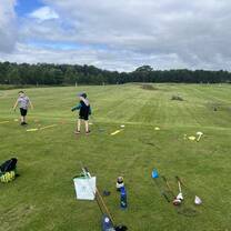 Participants in a Scotland golf study abroad program working on their golf swing outdoors.