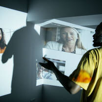 A student faces a wall where a virtual classroom is projected