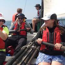 Students in a sailboat maneuvering oars.
