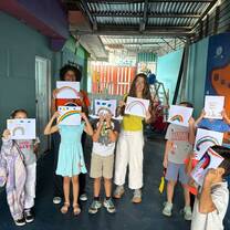 Teacher with students holding painted rainbows
