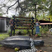 two people pose by a sign