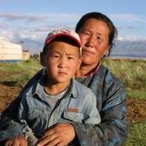 A Mongolian man and child pose near their yert.