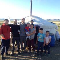Volunteers and nomads are standing in front of the Mongolian traditional dwelling.