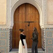 Two students standing in front of a wooden, carved door in the Medina