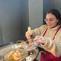 A girl mixes a paella in a workshop