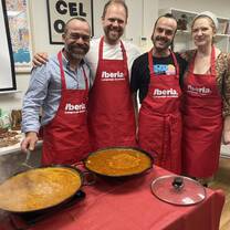 Four teachers in aprons next to a paella
