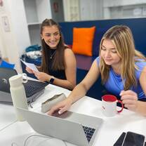 Two trainees sit at the table in the library planning their lessons