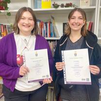 Two trainees hold their certificates