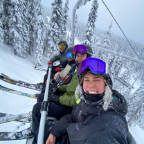 4 people on a ski lift in the snow