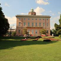 Pink historic villa at Parco Ciani in Lugano showcasing Italianate and Neoclassical architectural influences surrounded by greenery.