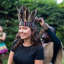 A local Tanzanian woman dressing a visitor in traditional ceremonial clothing and a handcrafted headband