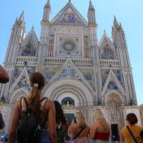 Group of students visiting Orvieto Cathedral in Italy, showcasing its ornate façade and Italian Gothic architectural style