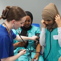 International students practising blood pressure monitoring and patient assessment during a supervised clinical skills course in the UK