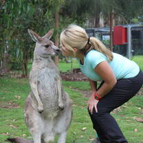 girl kneeling down to kiss kangaroo