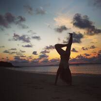 silhouette of person doing handstand on beach at sunset