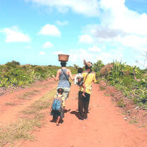 Women walking down a dirt road with baskets on their heads