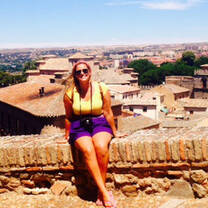 girl sitting on ledge overlooking spanish town 